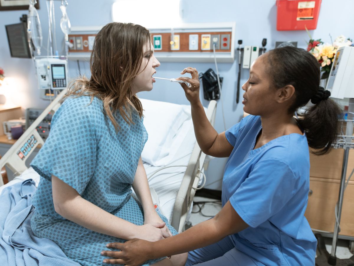 A nurse in scrubs caring for a patient in a hospital ward