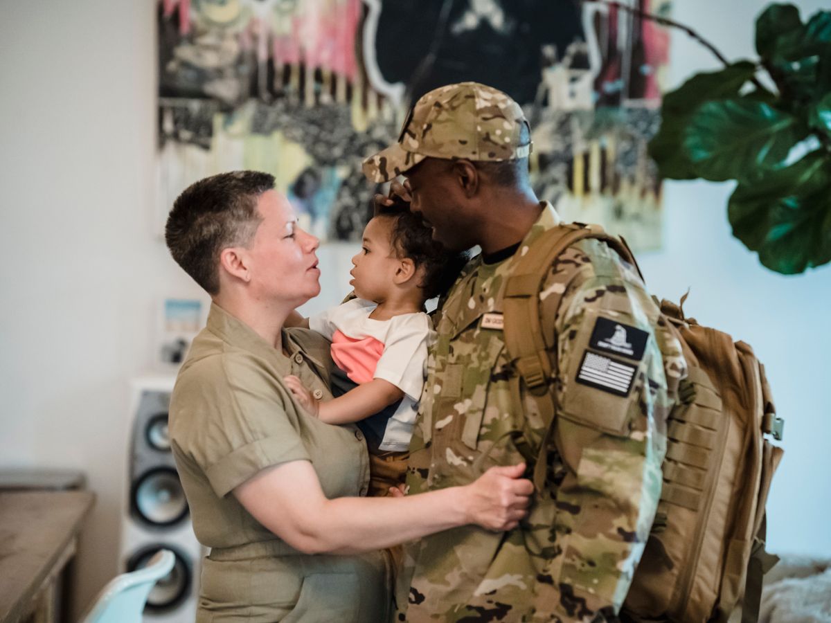 A soldier in uniform embracing family during a homecoming